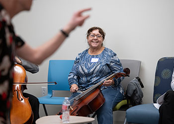 Cindy Garcia, who is a caregiver for her mom, plays a cello at Strokestra.