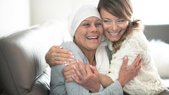 Woman wearing head scarf hugging younger woman